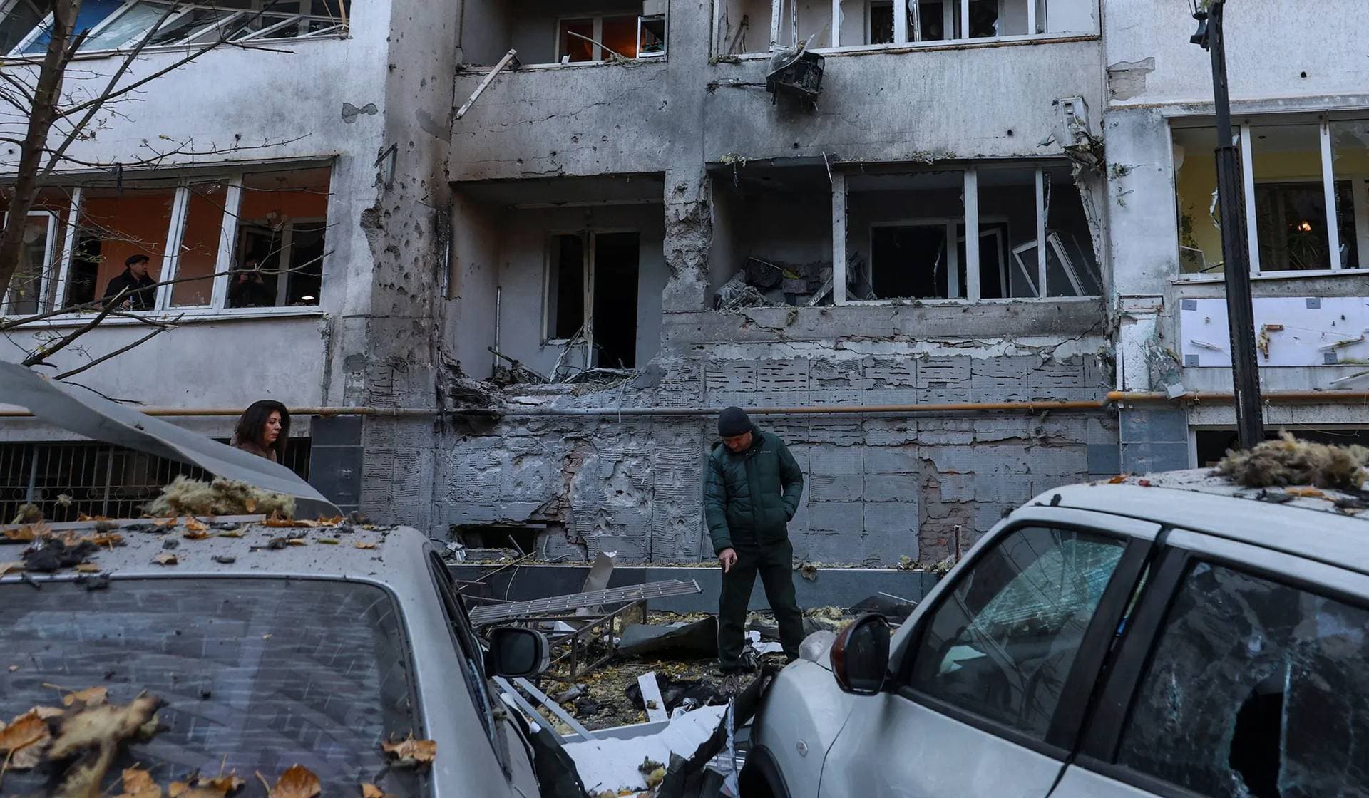 A resident points on remains of a kamikaze drone in front of an apartment building damaged during a Russian strike in Odesa