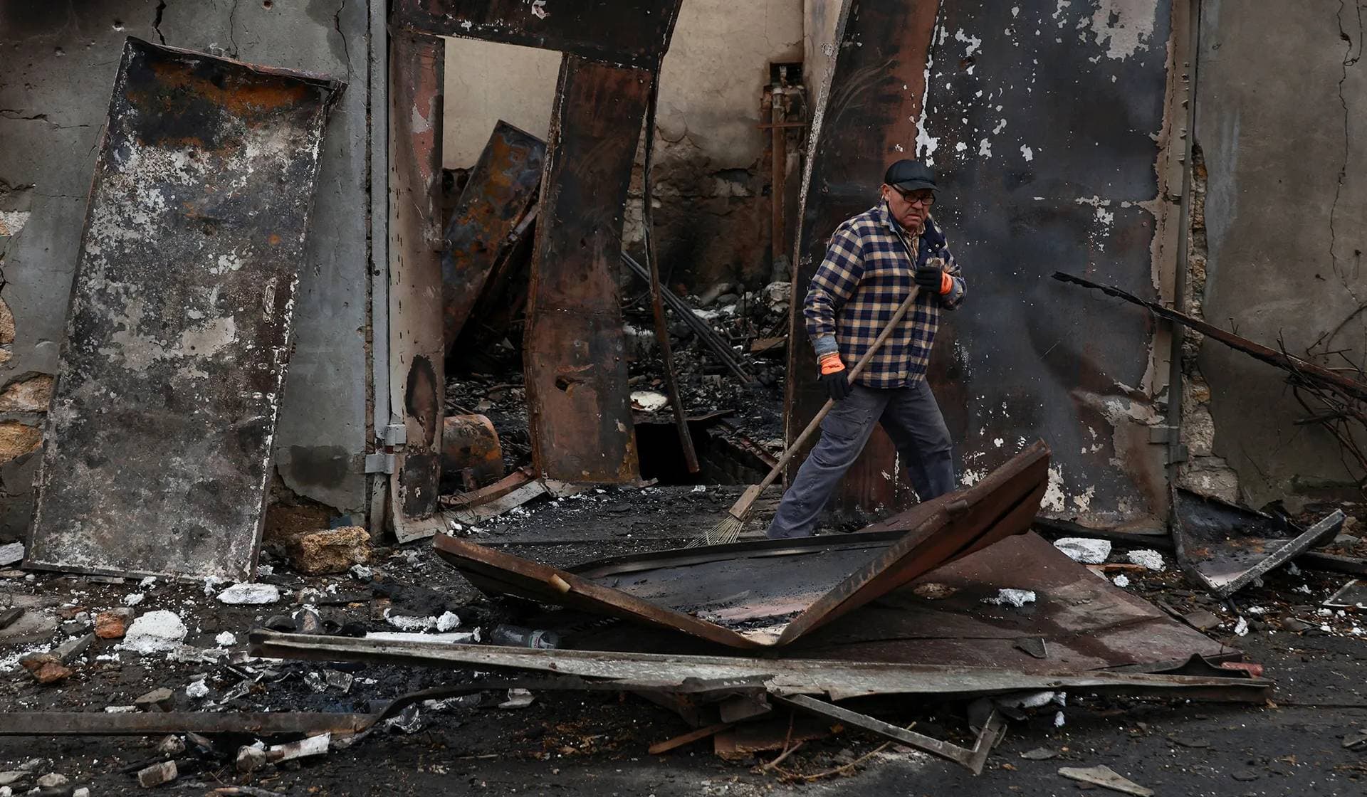 A resident removes debris from a garage heavily damaged by a Russian drone strike in Odesa