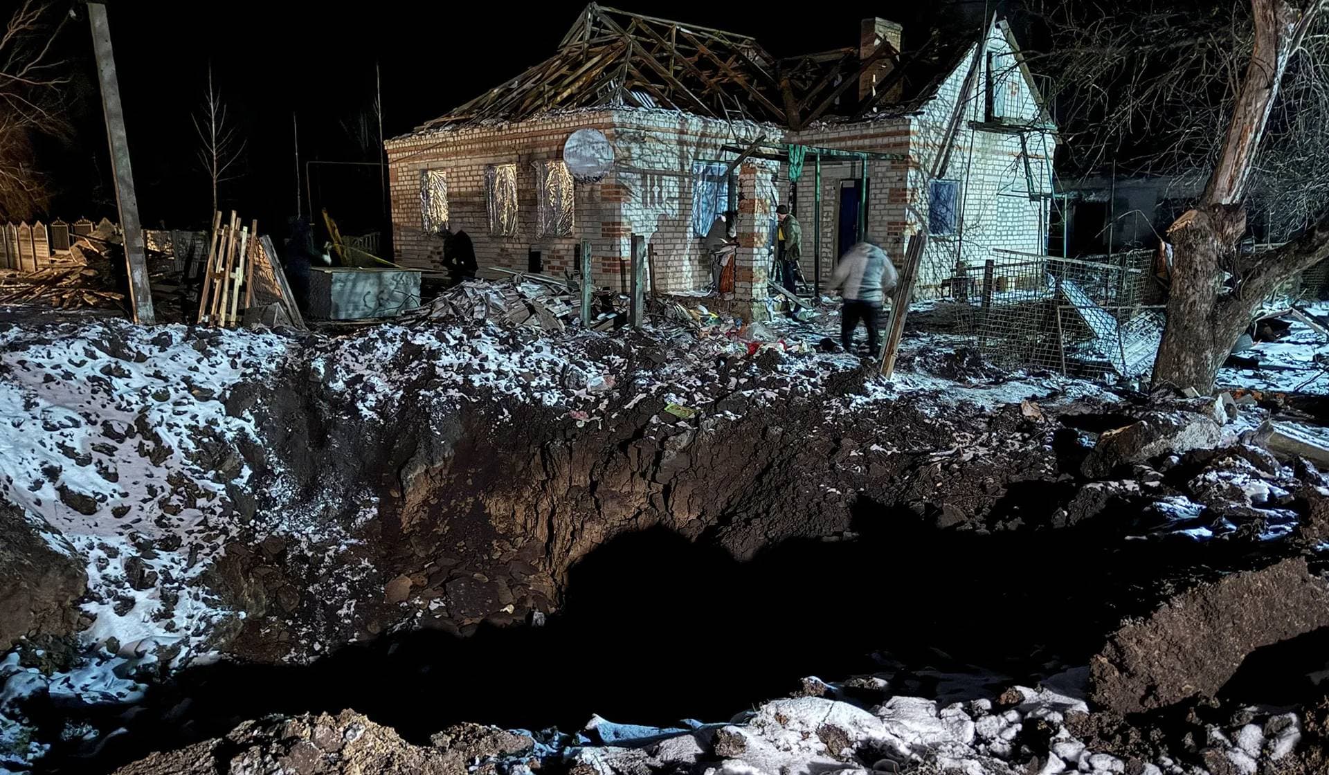 Local residents walk near a house damaged by a Russian missile strike in Pavlohrad
