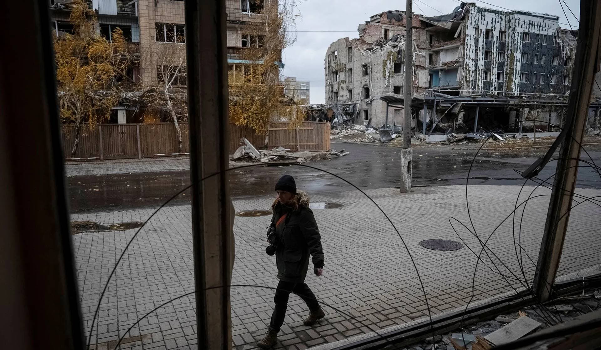 A photographer walks past buildings damaged by a Russian military strike in Pokrovsk