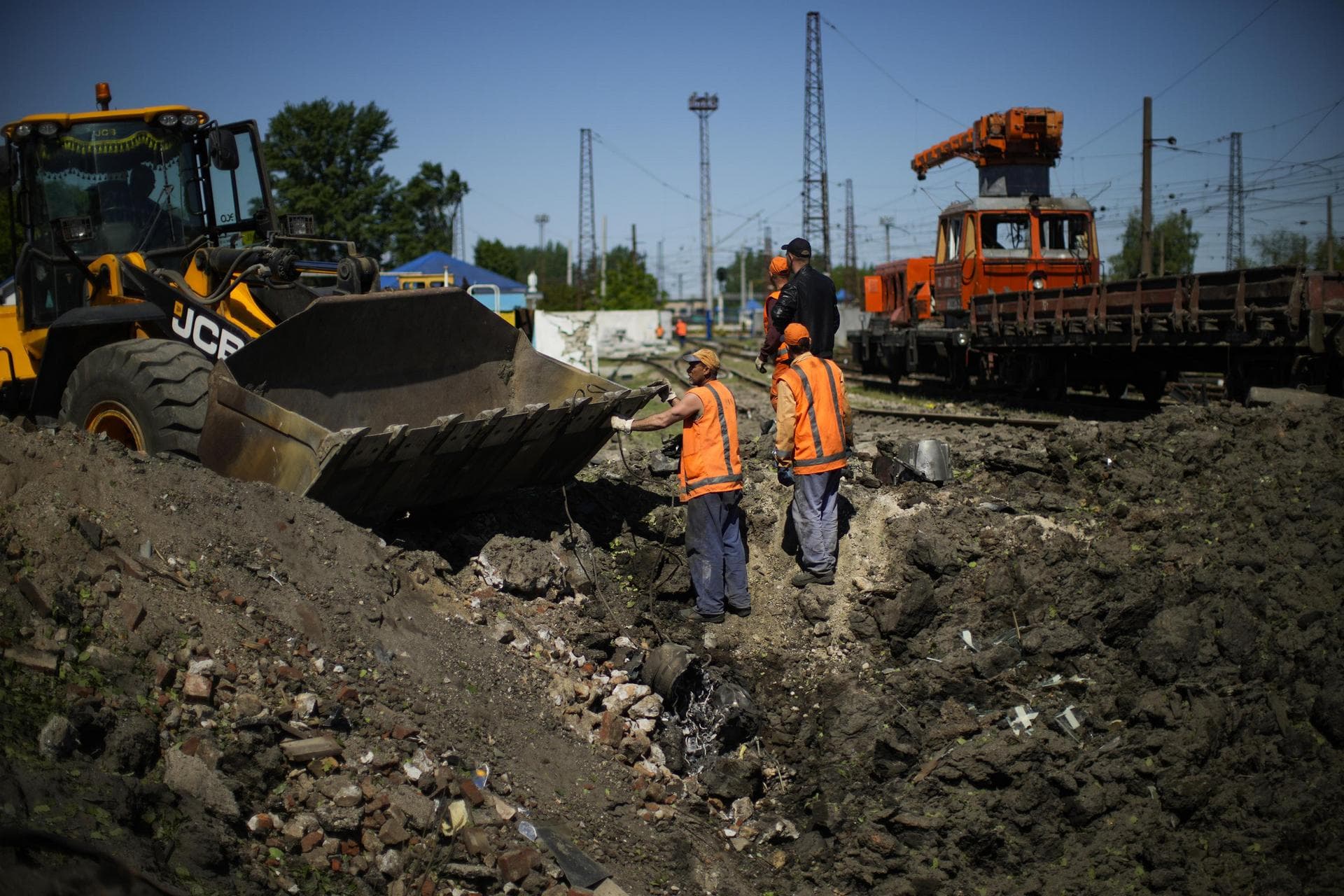 Workers remove pieces of a rocket from a crater after a Russian strike in Pokrovsk