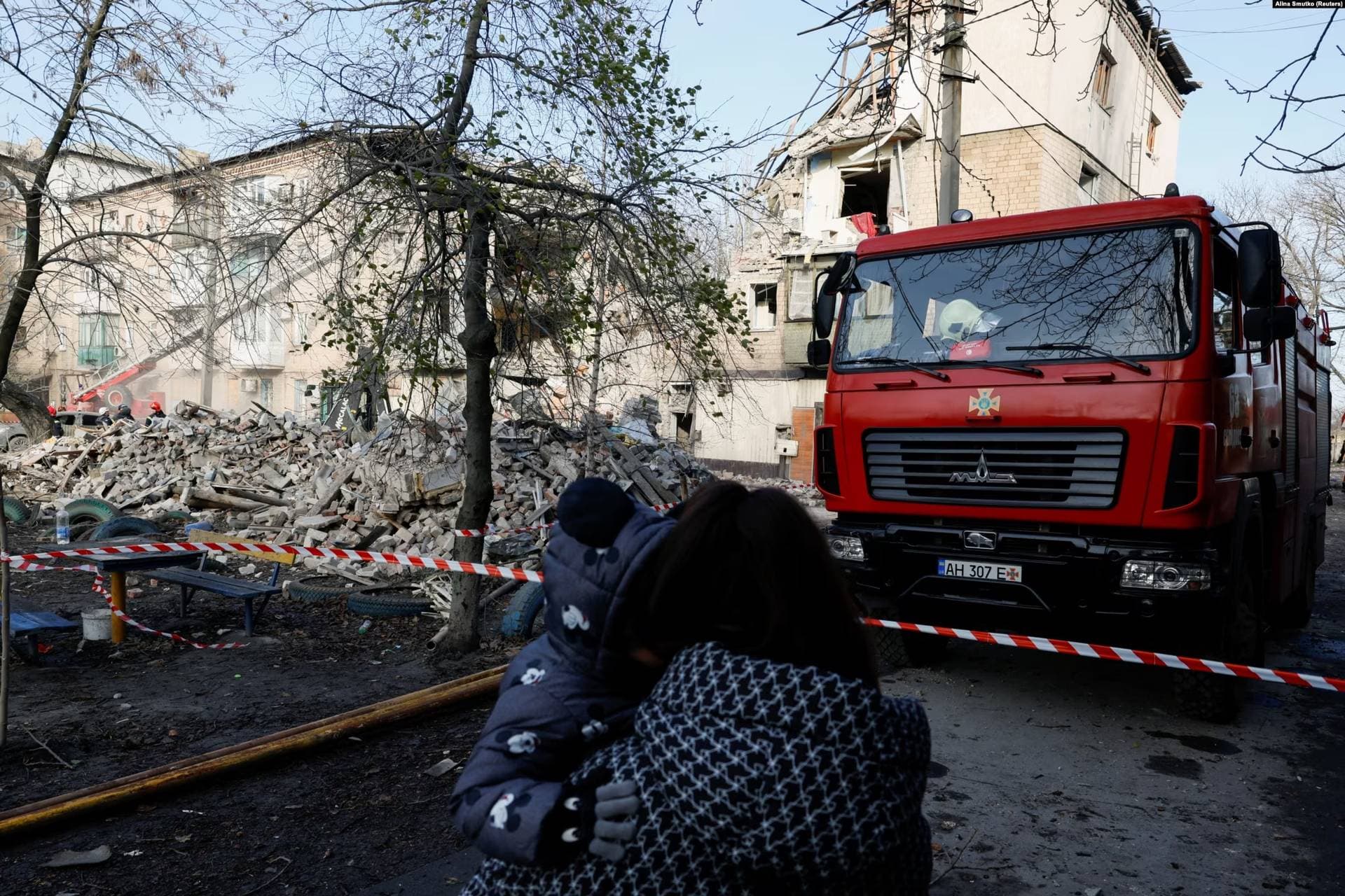A woman and a child look at a damaged residential area in the town of Selydove
