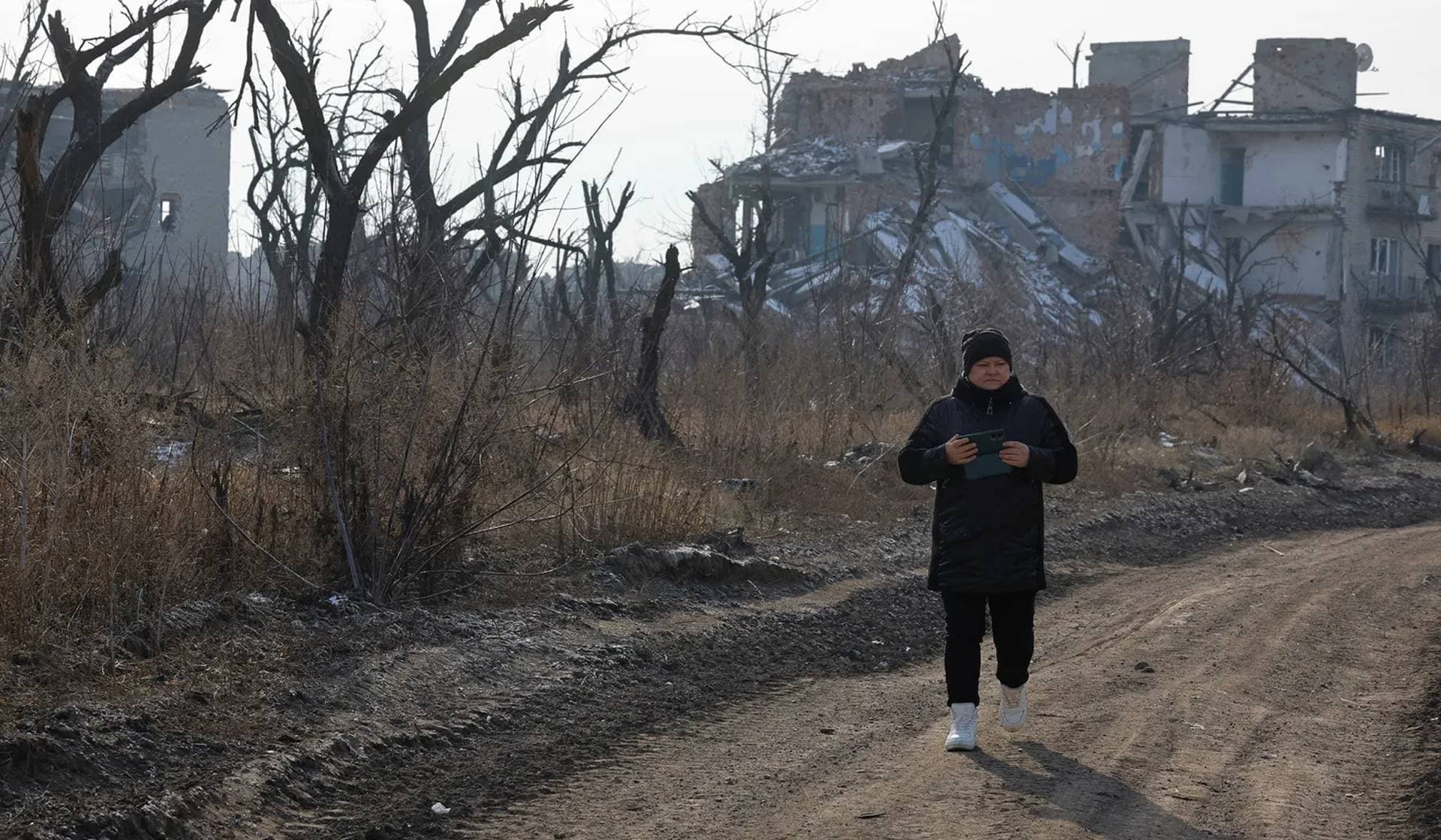 Maria Seryogova walks past ruins of buildings as she comes to visit her apartment destroyed in Pisky