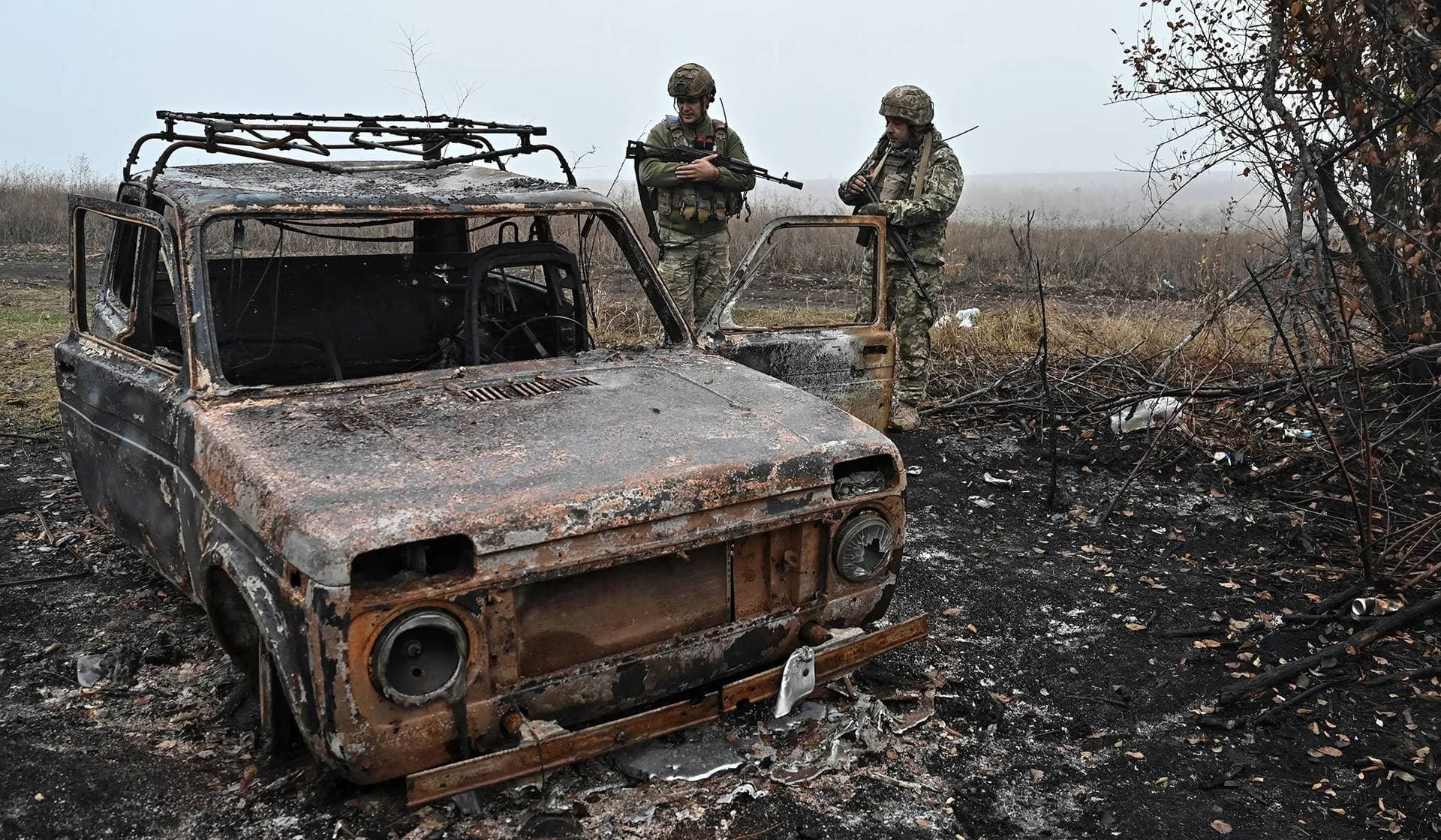 Ukrainian servicemen inspect a destroyed vehicle outside the village of Robotyne
