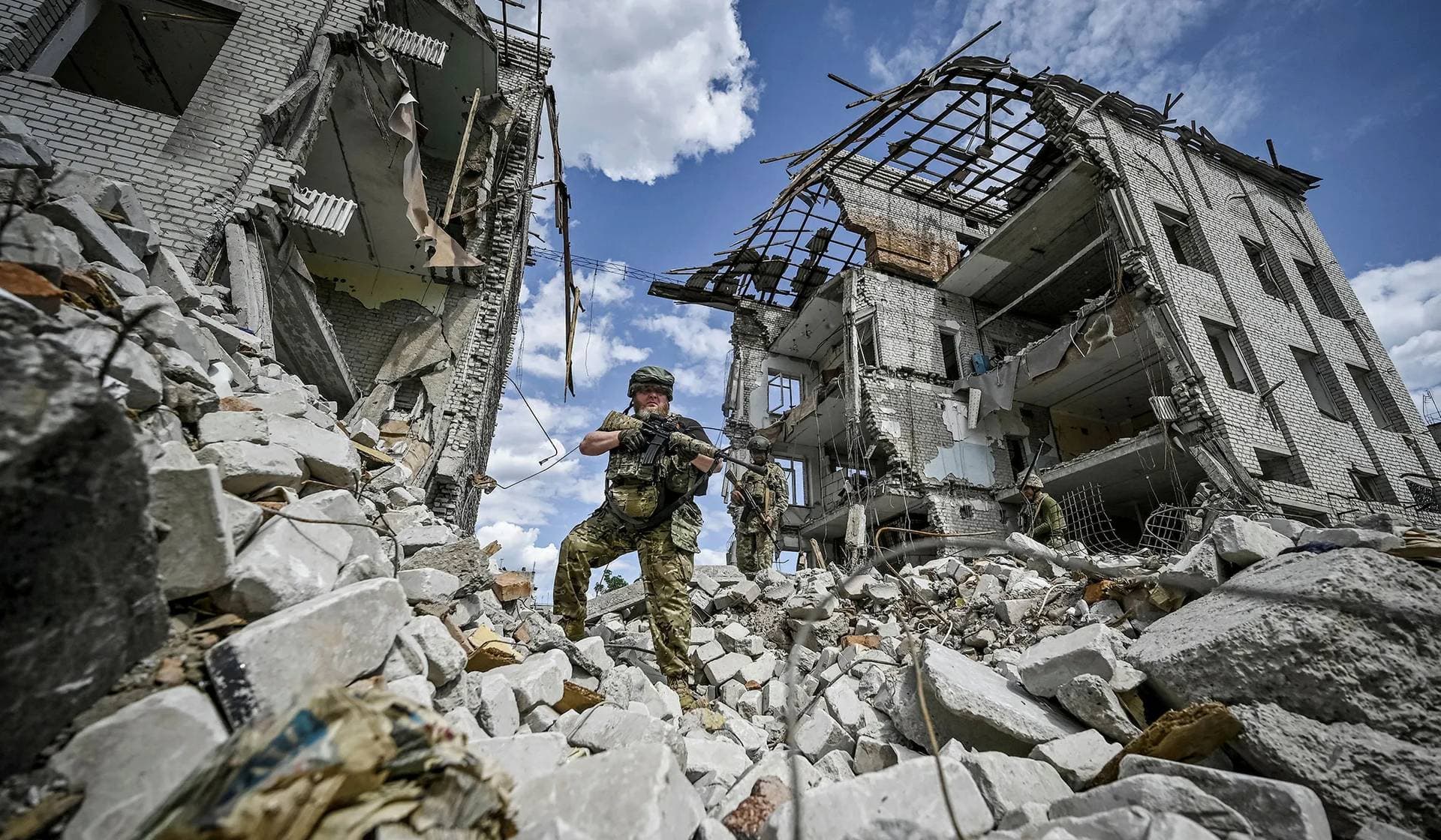 Ukrainian servicemen patrol an area heavily damaged by Russian military strikes in Orikhiv