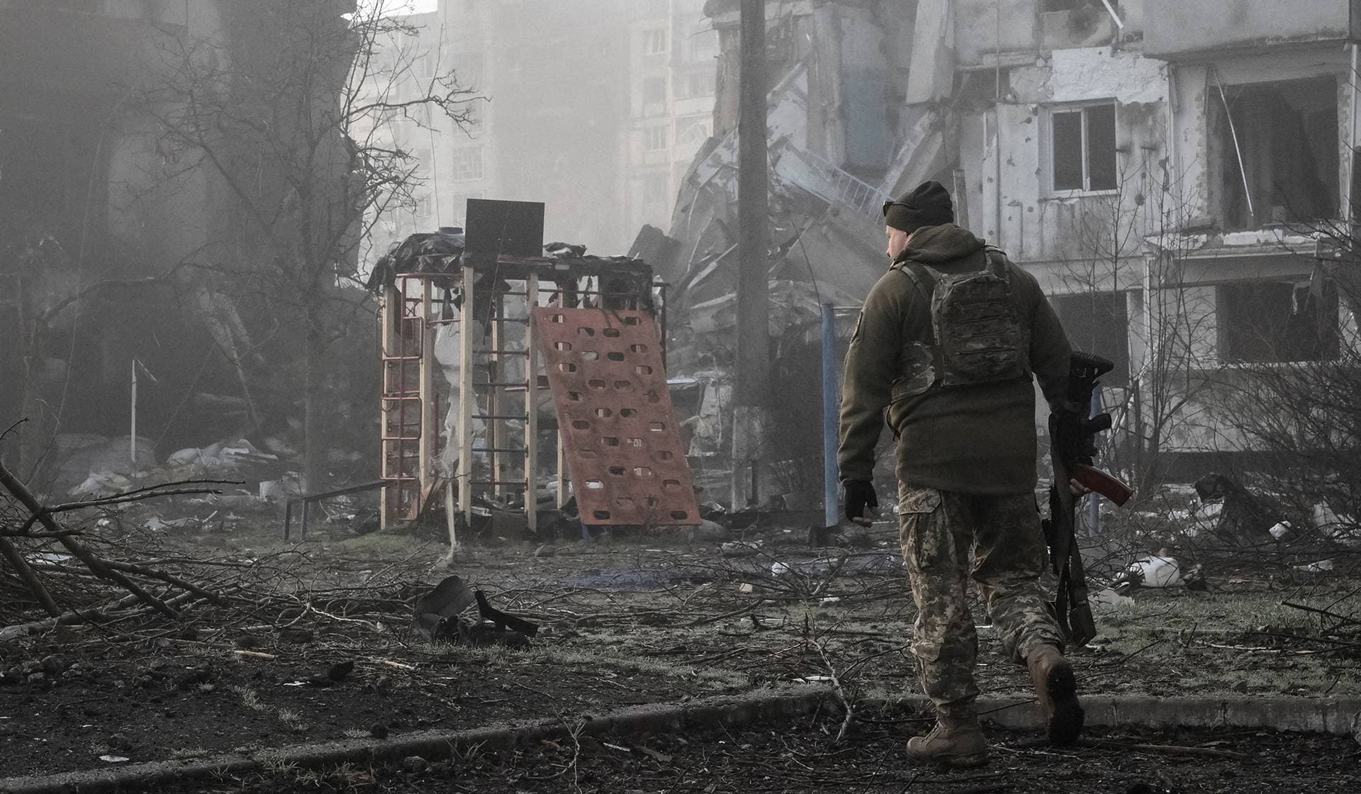 A Ukrainian service member walks near residential buildings damaged by Russian military strikes in the frontline town Orikhiv