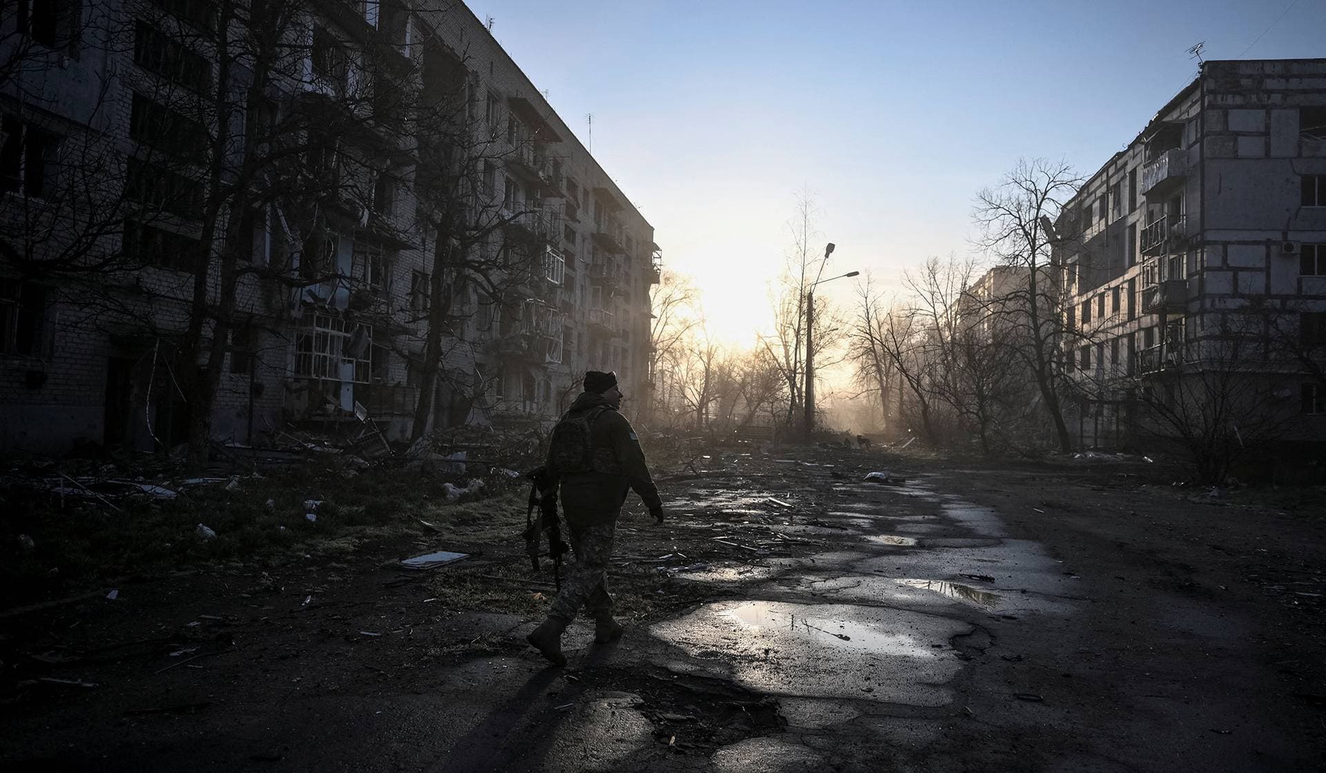 A Ukrainian service member walks near residential buildings damaged by Russian military strikes in the frontline town Orikhiv