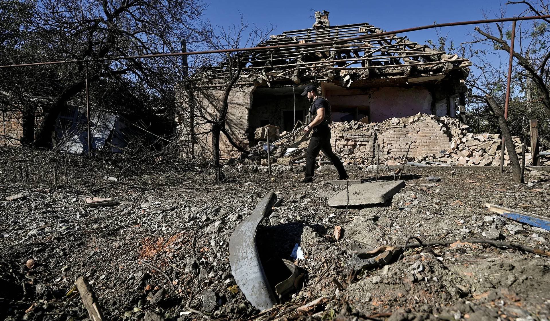 A police officer inspects a house heavily damaged by a Russian military strike in Orikhiv