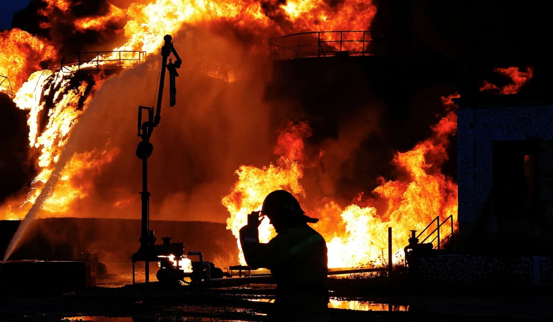 A firefighter works to extinguish fire following recent shelling at an oil storage facility in Shakhtarsk