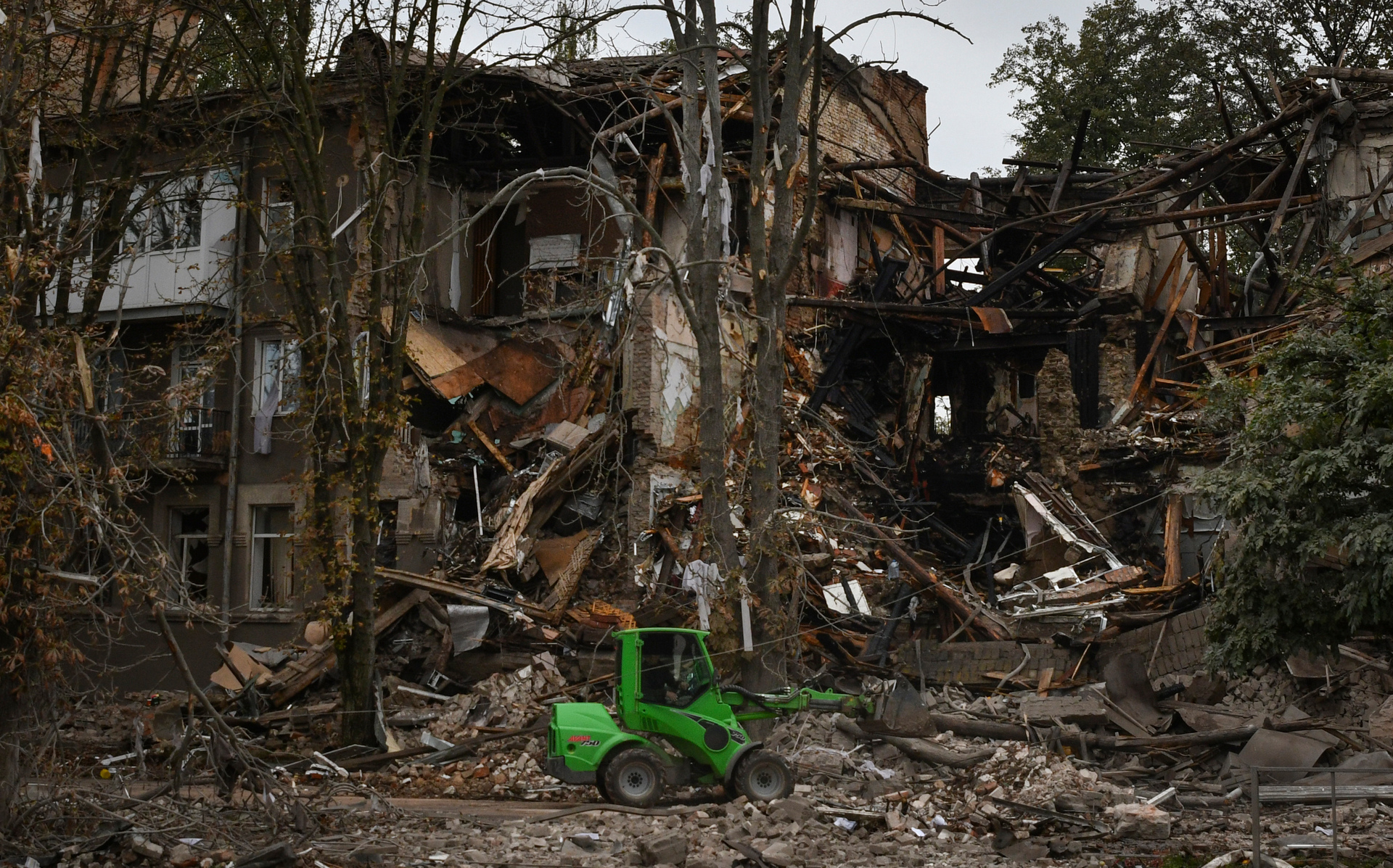 Communal workers clean the debris from the street in front of a heavily damaged building after a Russian attack in Sloviansk
