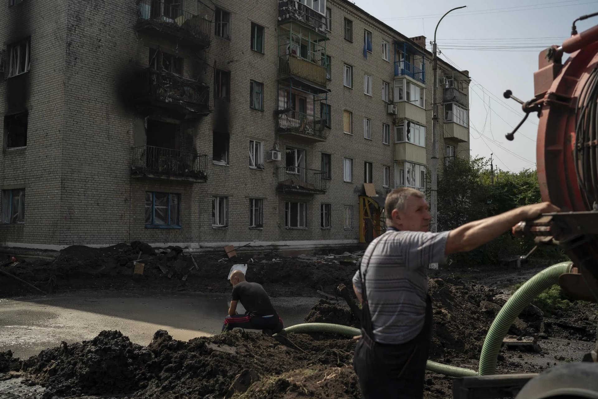 Workers drain water from a crater created by an explosion that damaged a residential building after a Russian attack in Slovyansk