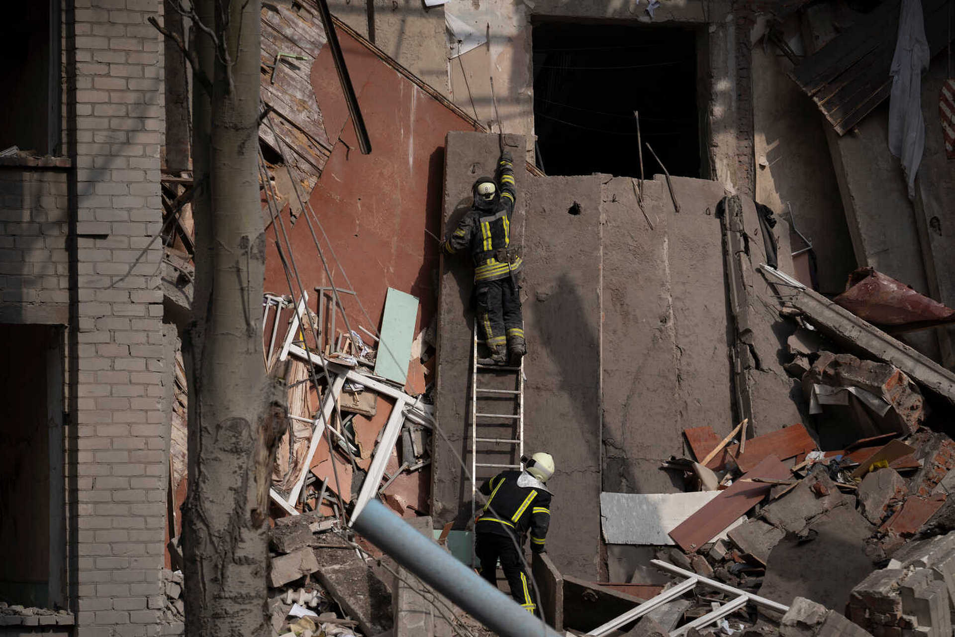 Rescue workers clear the debris at the scene where a woman was found dead after a Russian attack that heavily damaged a school in Mykolaivka