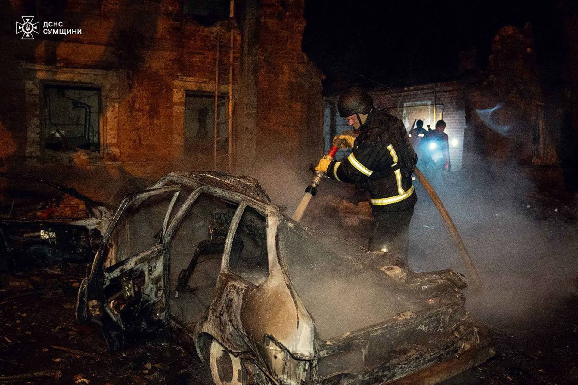 Firefighters work at a site of a residential area hit by a Russian drone strike in Sumy
