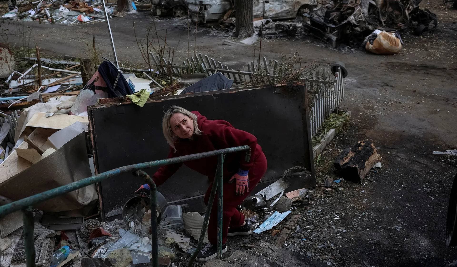 A resident throws broken glass from windows of her apartment building damaged by a Russian drone strike in Shakhtarske