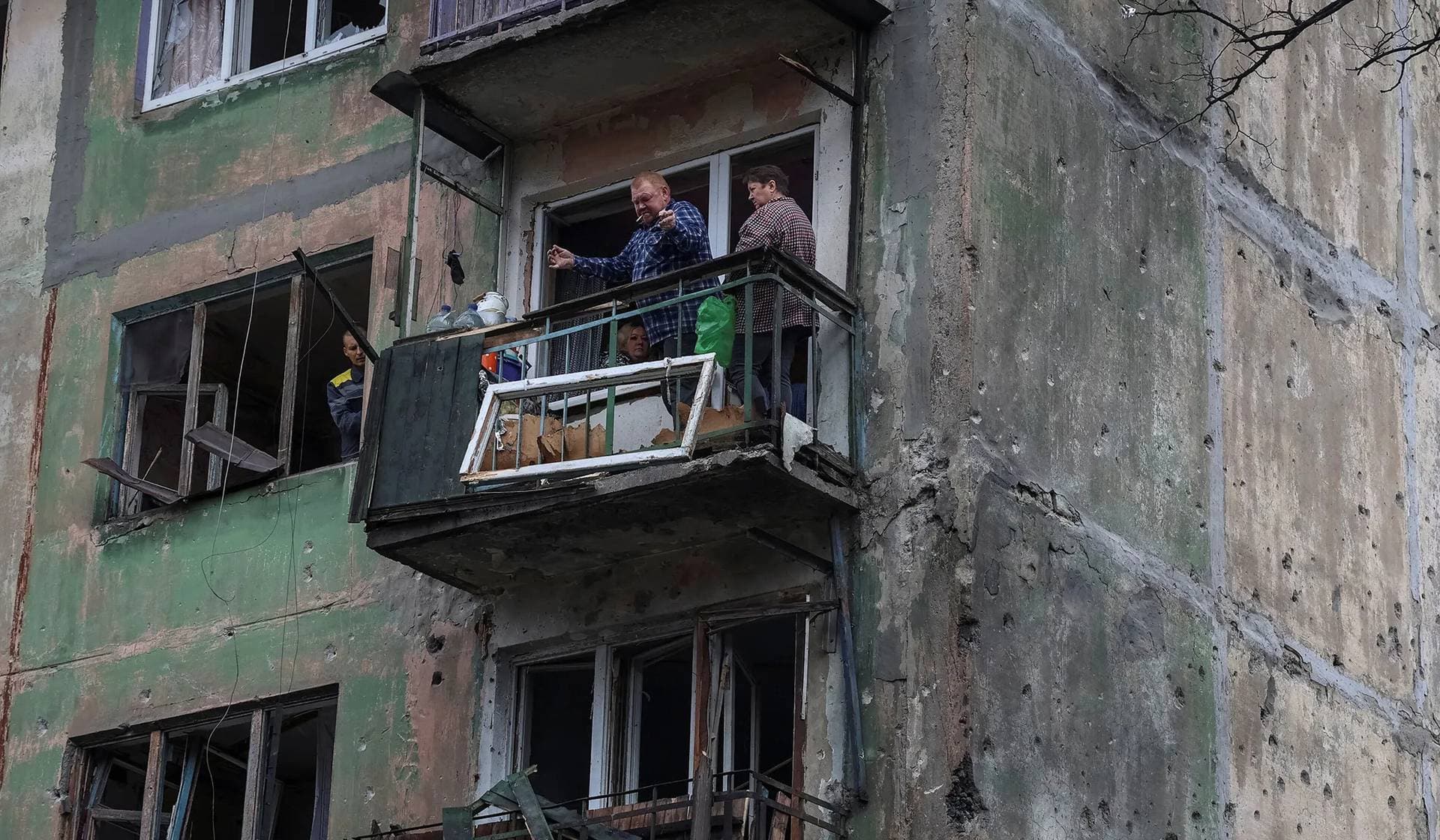 Residents stand at the balcony of their apartment in a building damaged by a Russian drone strike in Shakhtarske
