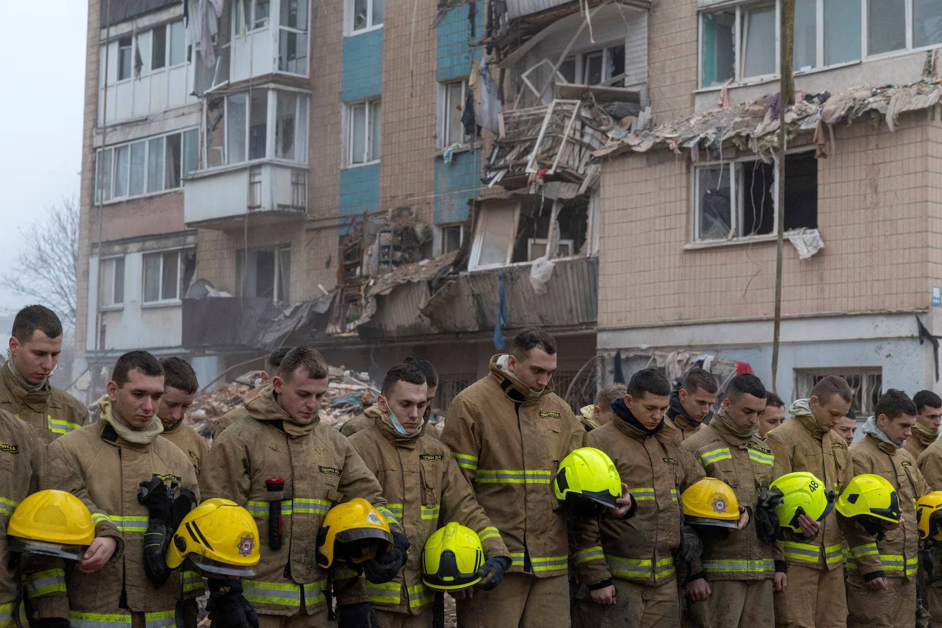 Firefighters observe a minute of silence to honour the victims of Russian aggression at the site of an apartment building that was hit yesterday by a Russian missile in Ternopil