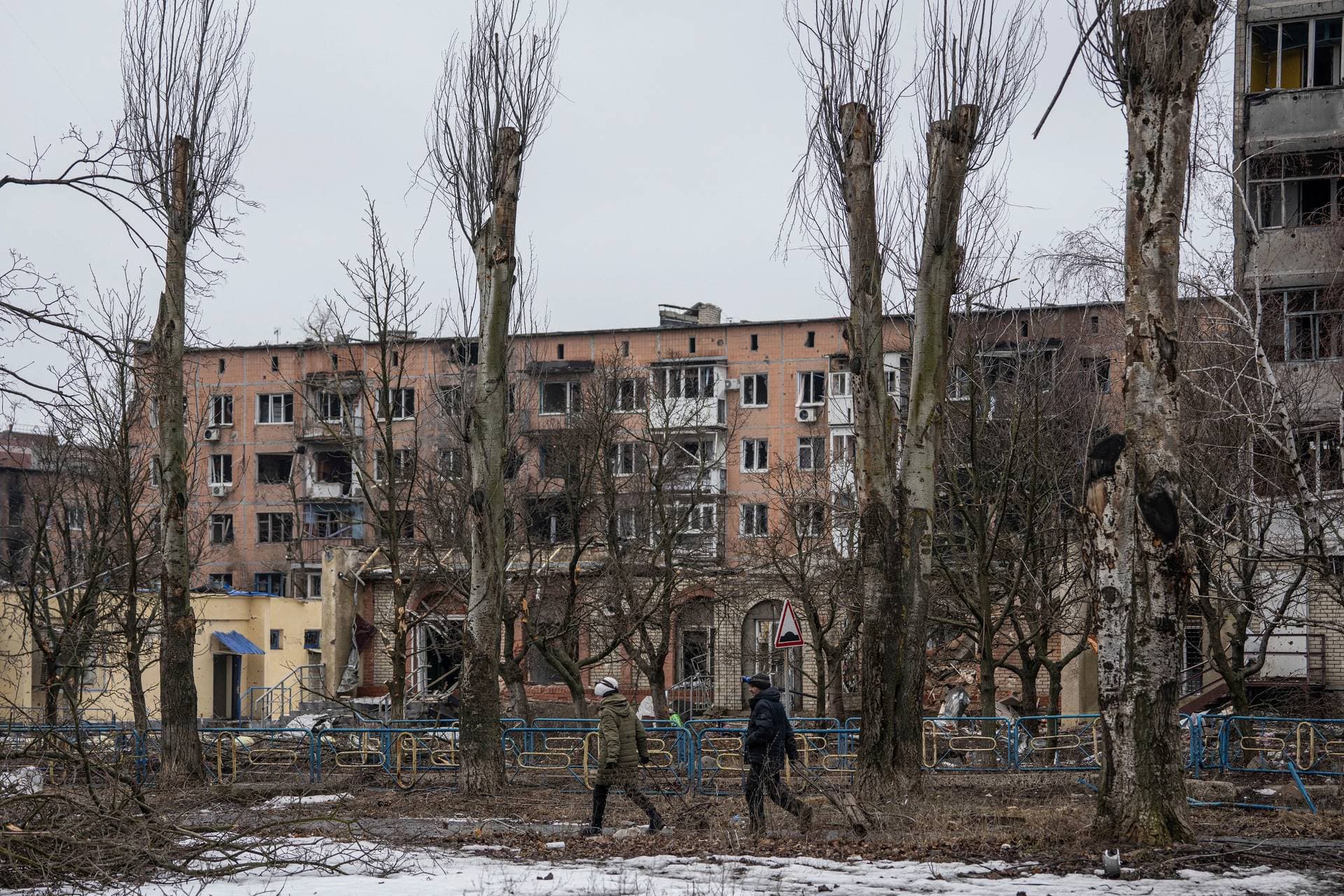 Local resident who decided to stay in the city walk on a street in front of the residential building in the frontline city of Vuhledar