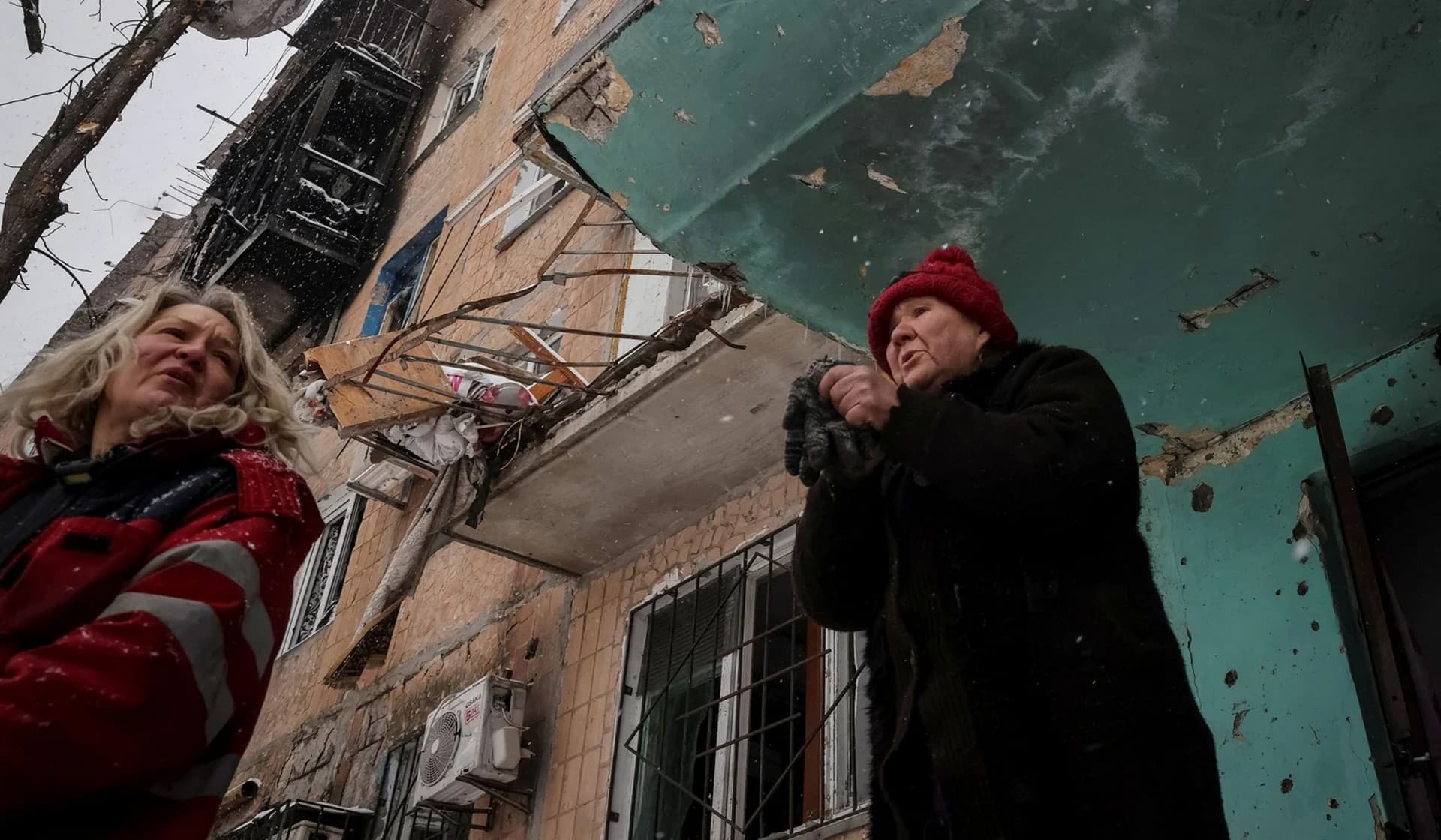 Local residents stand near their building which was damaged by a Russian military strike in the front line city of Vuhledar