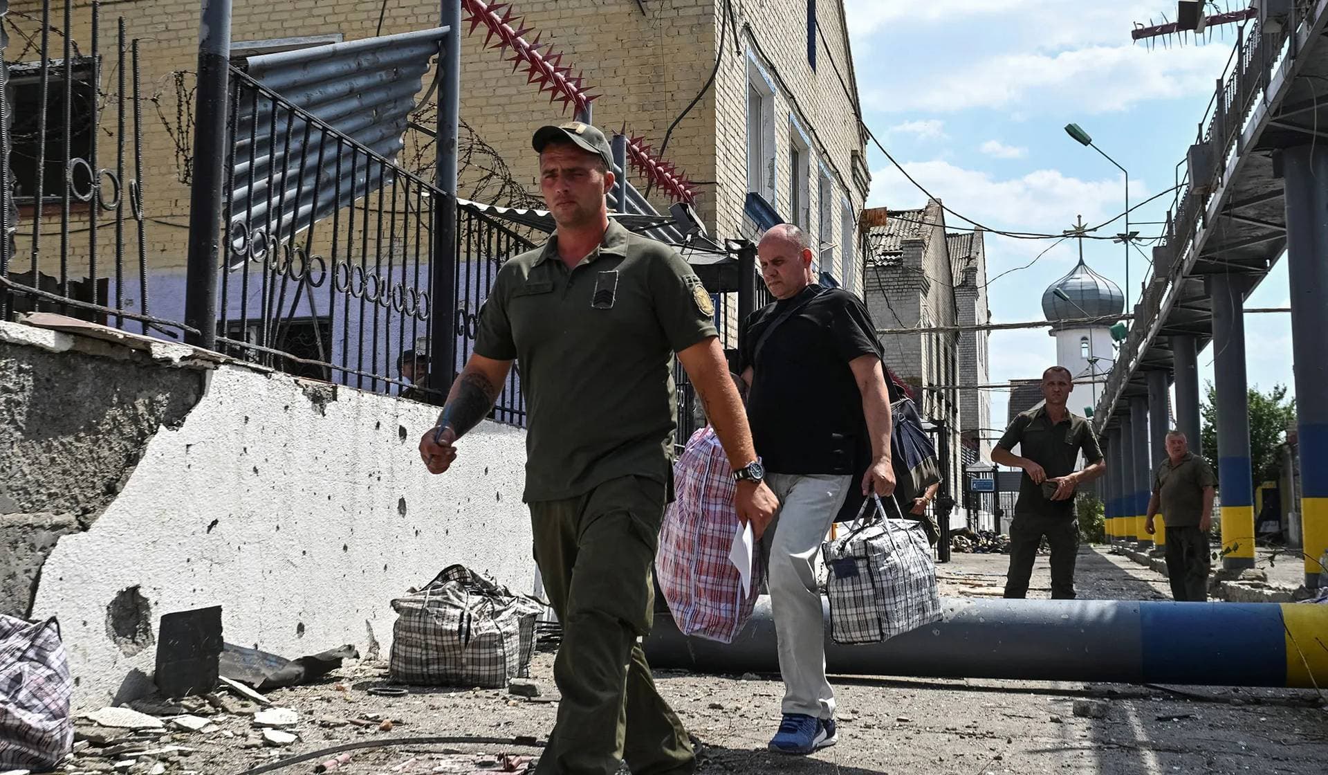 A serviceman accompanies a prisoner at the site of the penal colony hit by a Russian air strike in Zaporizhzhia Region