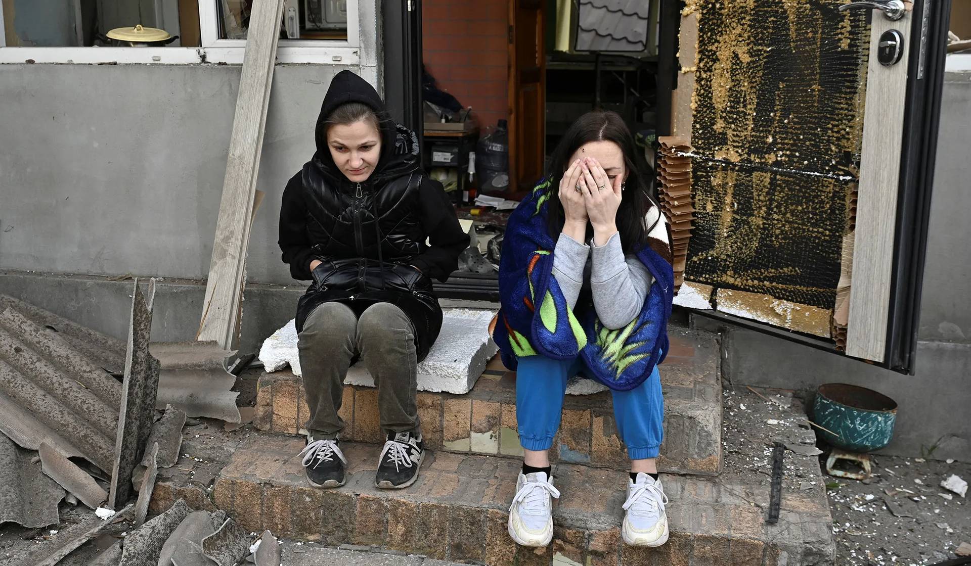 Women react next to their house damaged by a Russian air strike in Zaporizhzhia