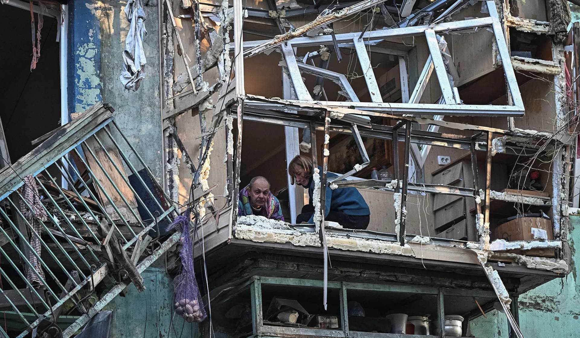 Residents clean the balcony of their apartment in their building damaged by a Russian drone strike in Zaporizhzhia