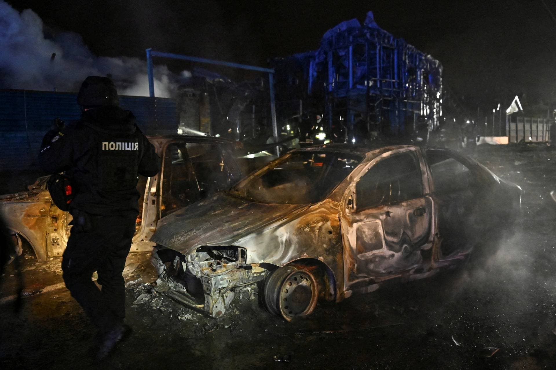 A police officer inspects destroyed cars at the site of a Russian air strike in Zaporizhzhia