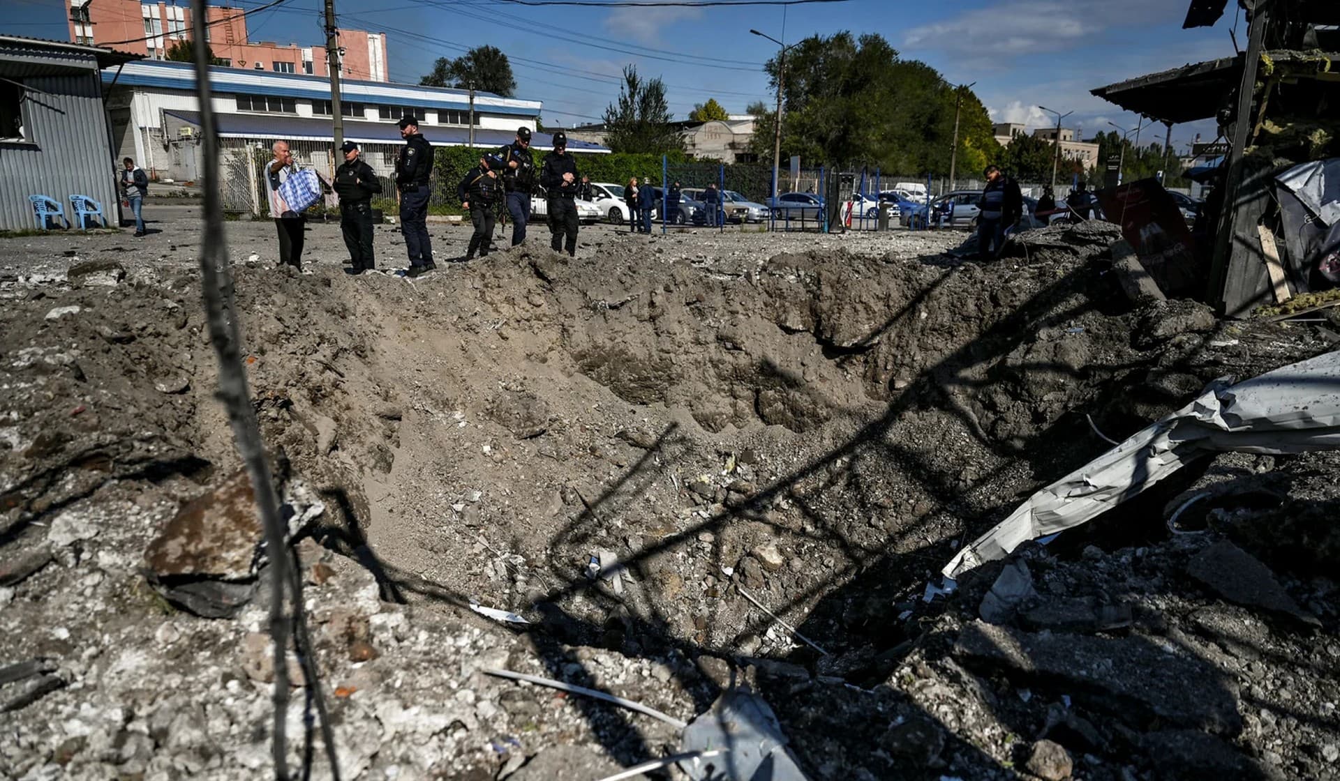 Police officers stand next to a crater left by a Russian missile strike in Zaporizhzhia