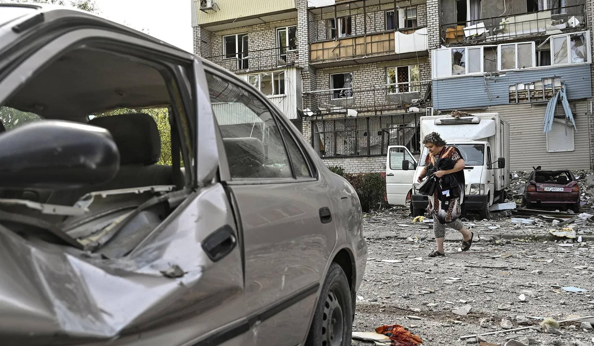 A woman walks next to her apartment building damaged by a Russian air strike in Zaporizhzhia