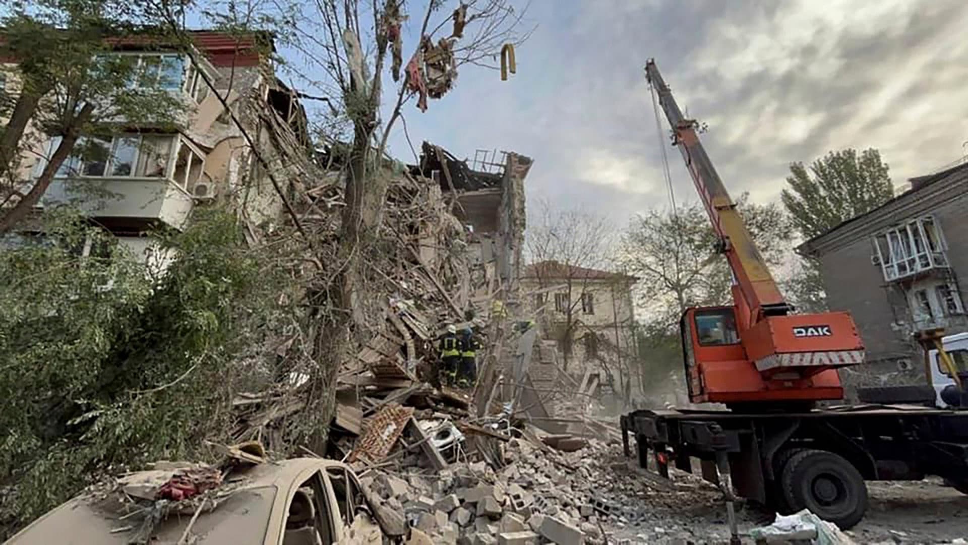rescuers work on a scene of building damaged by shelling in Zaporizhzhia