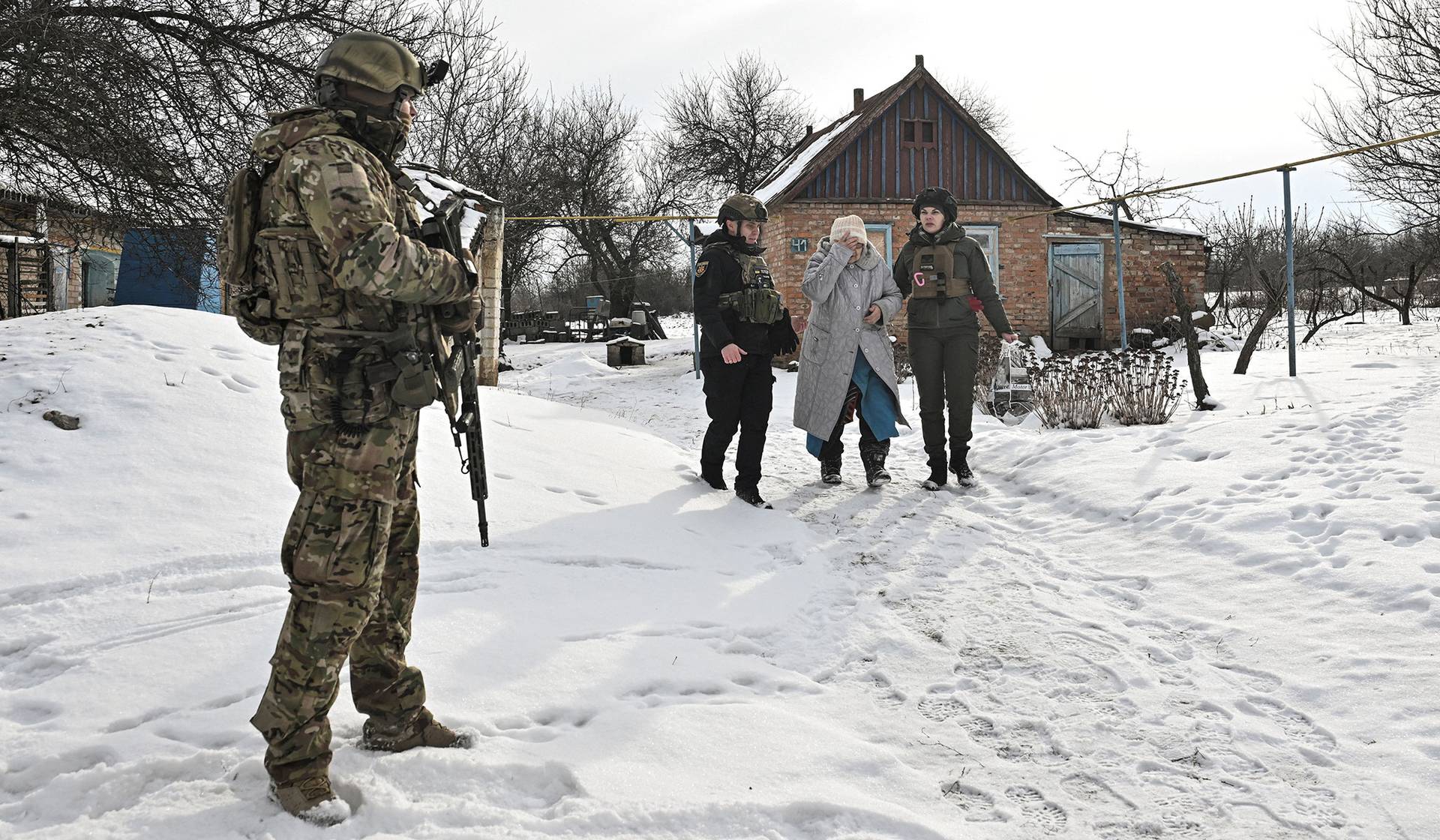 Police officers assist a resident during an evacuation from a frontline village of Yurkivka